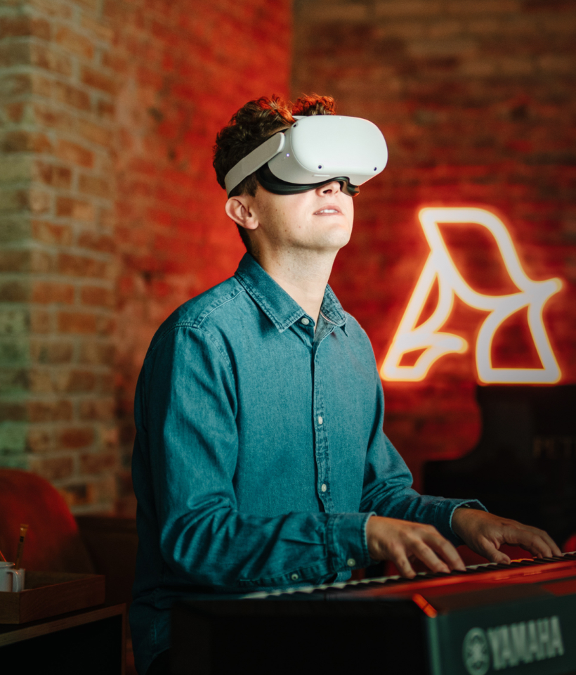 A man playing on a piano with a VR headset.